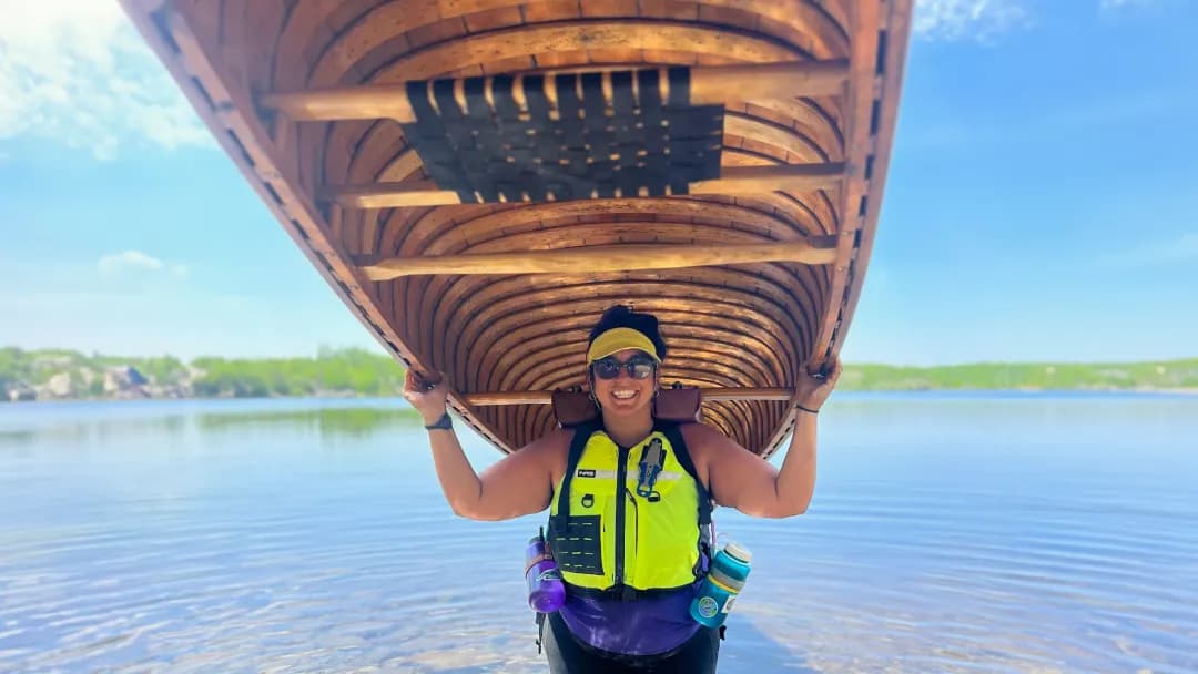 Cory Maria Dack holds up a giant wooden canoe