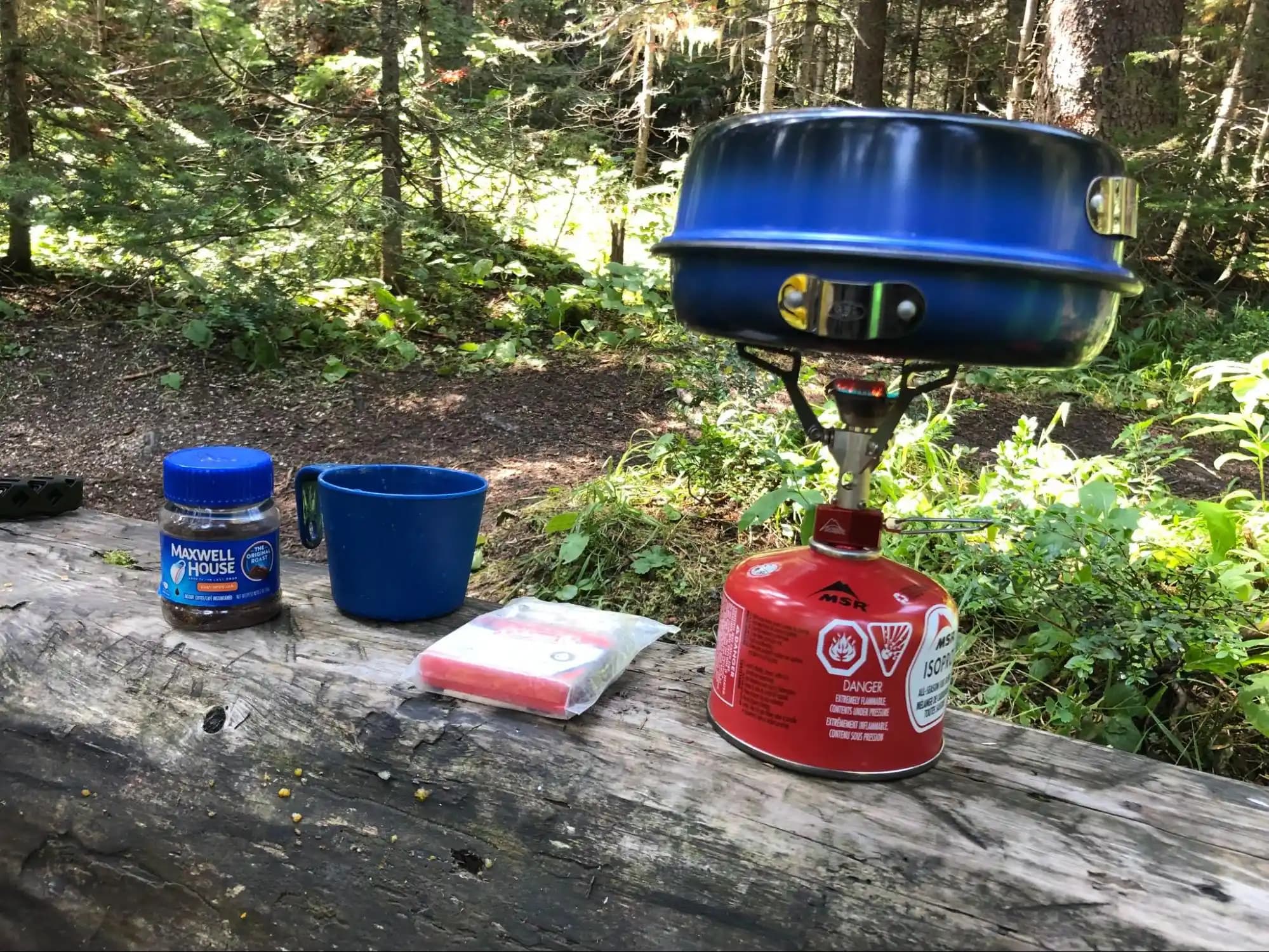 a camp stove being used to boil water for a cup of coffee.
