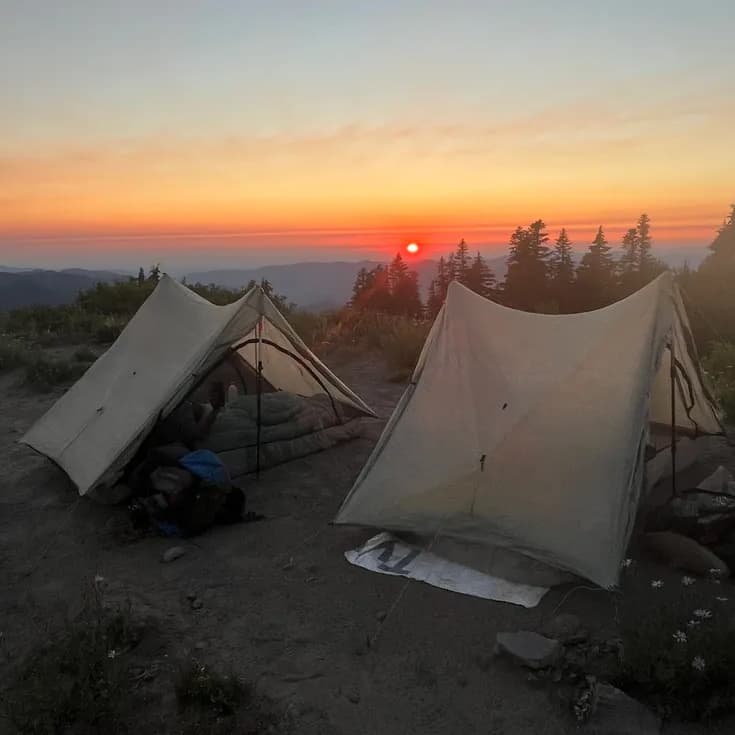 campsite on a mountain overlooking a red sunset