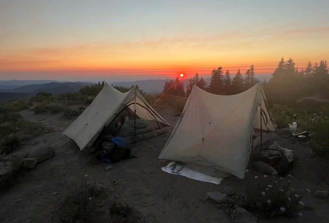 campsite on a mountain overlooking a red sunset