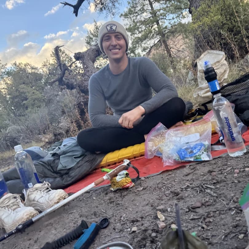 a backpacker sitting on the ground with well managed trash leave no trace