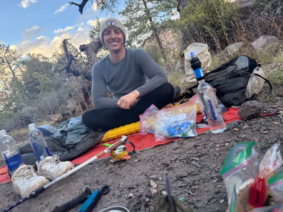 a backpacker sitting on the ground with well managed trash leave no trace