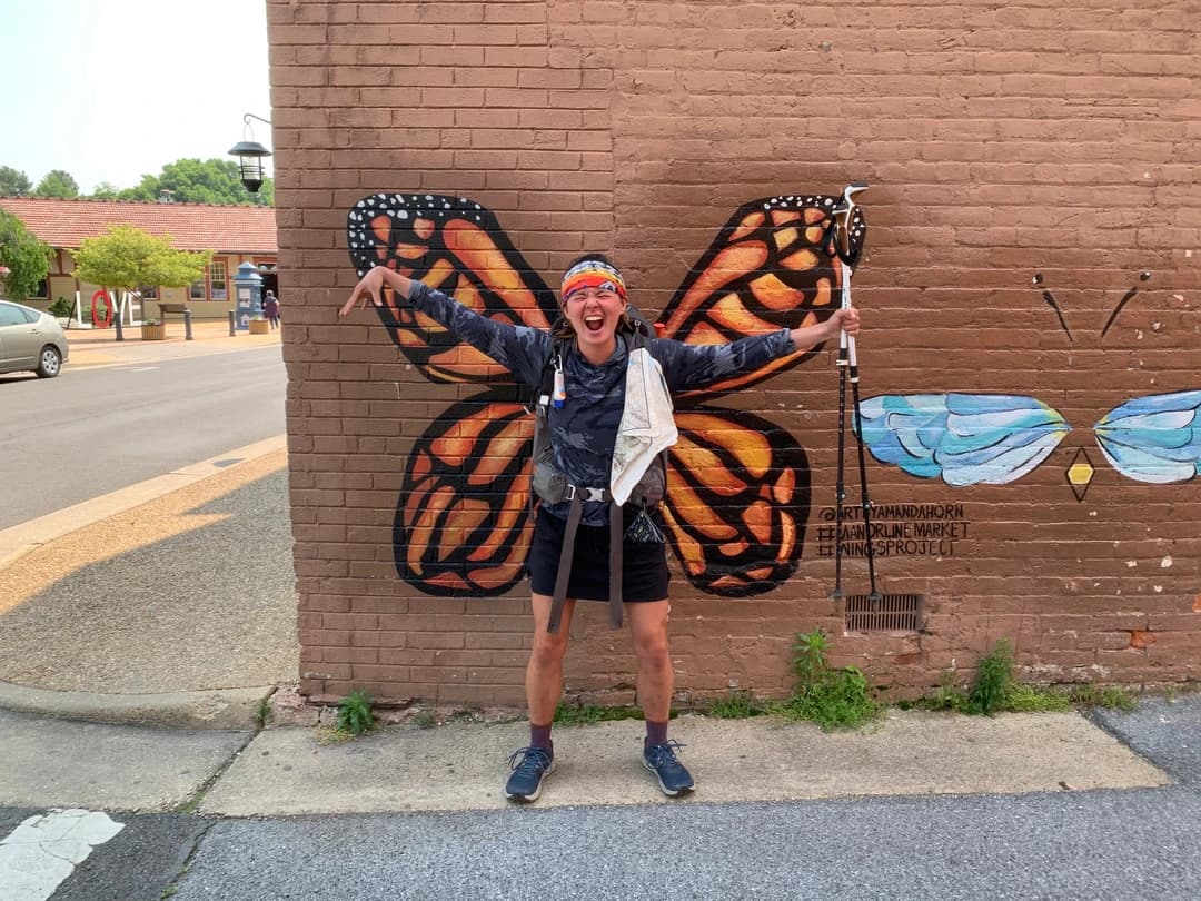 Nicole Kemon standing in front of a butterfly mural on a brick wall