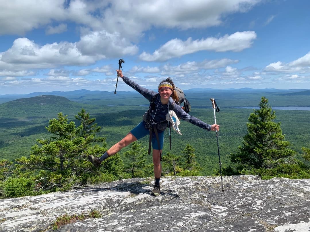 Nicole Kemon doing a one legged jumping jack on top of a cliff