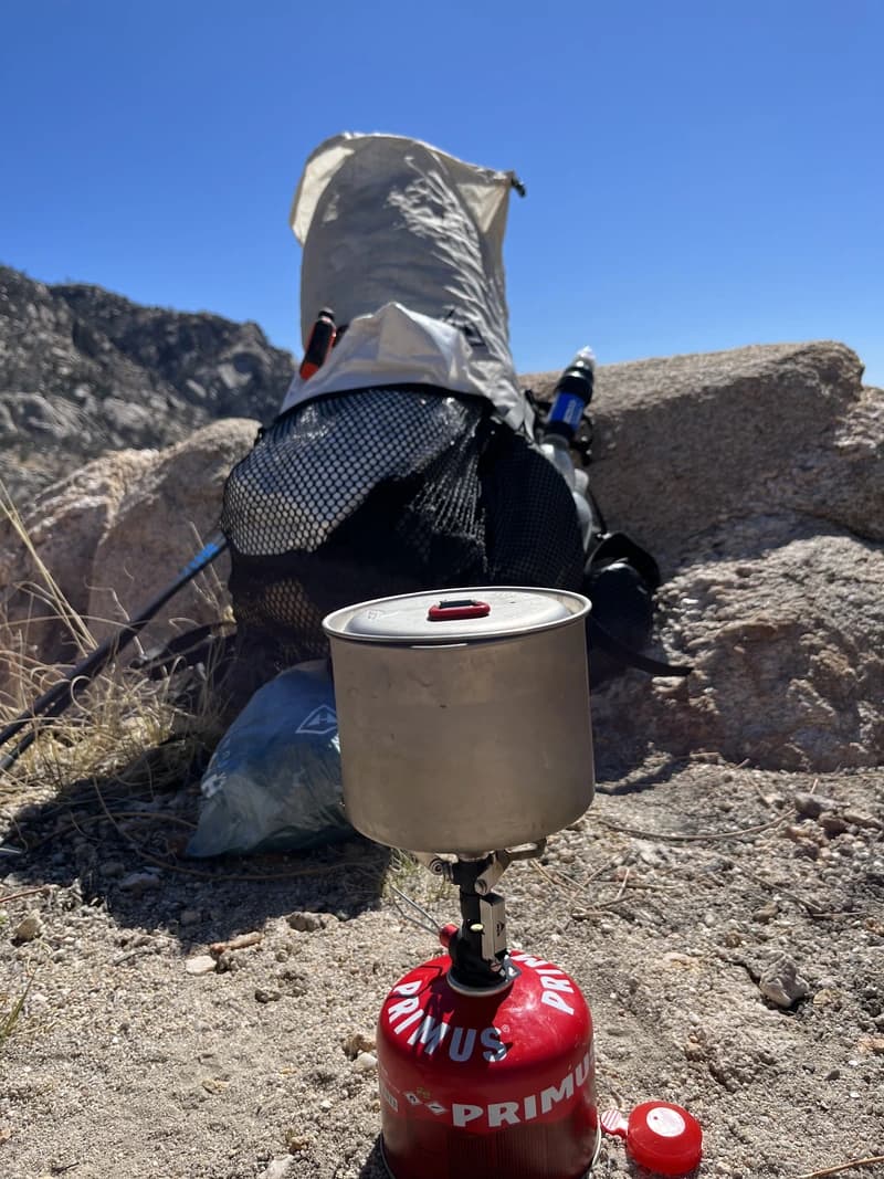 a camp stove in front of a backpack