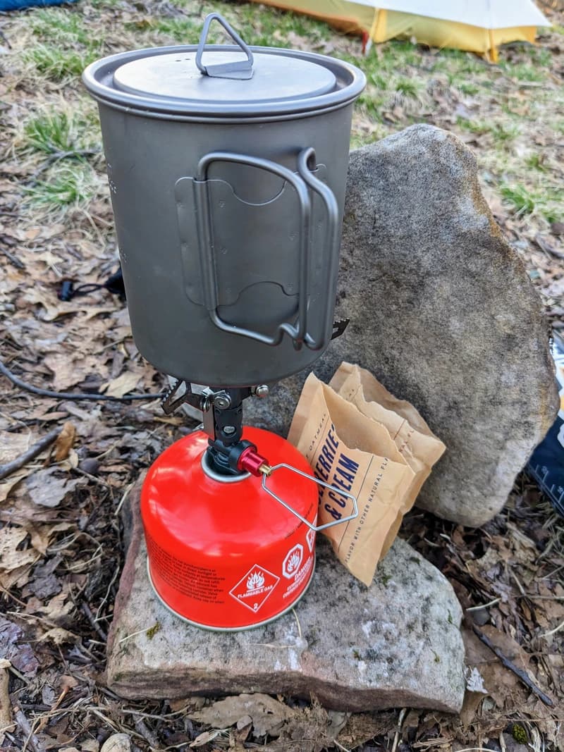 a classic camping stove with a red butane tank