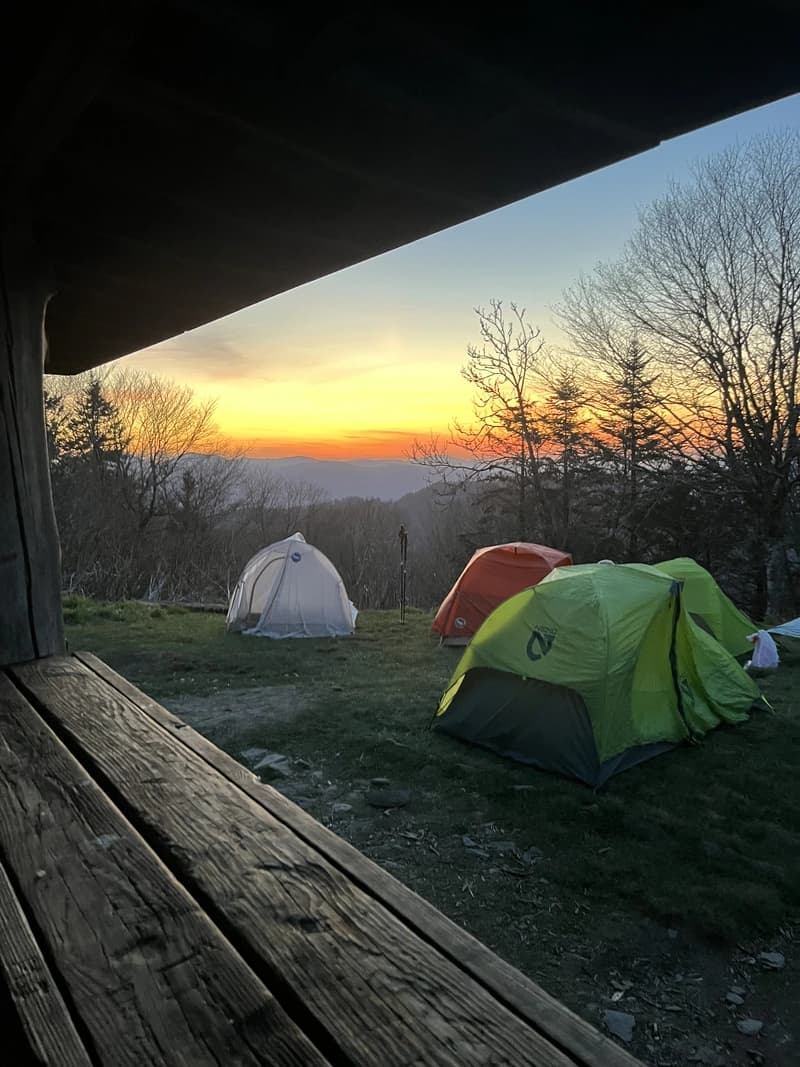 a group of tents with a sunset in the background