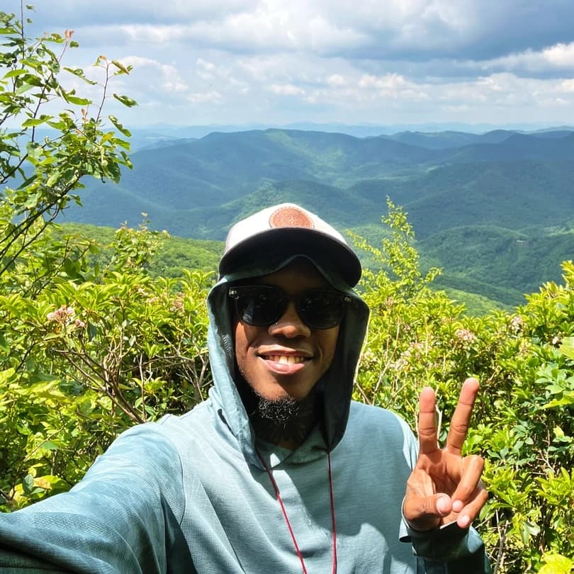 Justin Tucker making a peace sign over a green valley