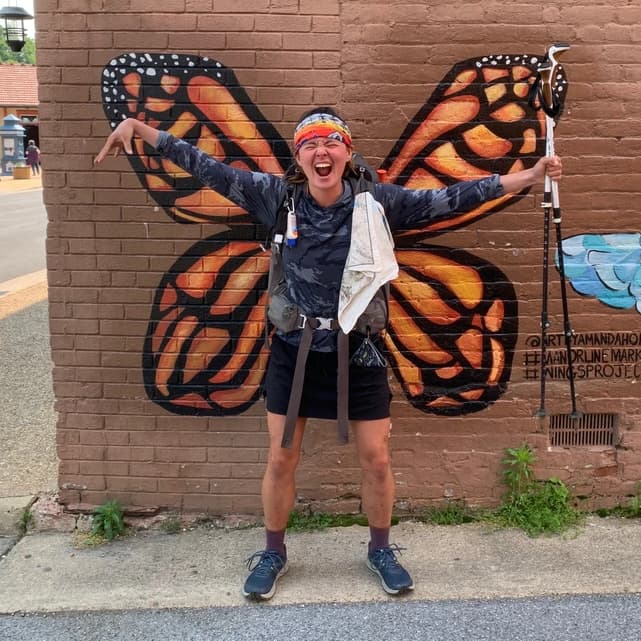 Nicole Kemon standing in front of a butterfly mural on a brick wall